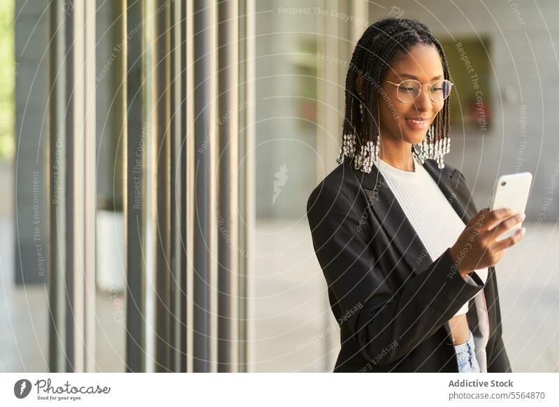 Lächelnde Geschäftsfrau, die ein Mobiltelefon benutzt und einen Laptop hält Frau Smartphone Browsen Eingang Unternehmer modern Büro Türöffnung benutzend