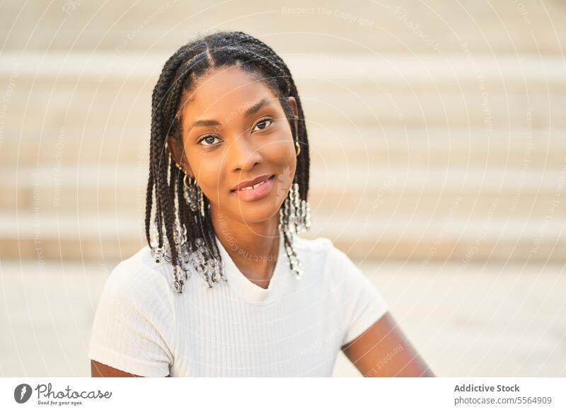 Lächelnde afroamerikanische Frau, die auf einer Treppe sitzt und in die Kamera schaut Flora jung lässig sitzen sich[Akk] entspannen Geflecht Stil idyllisch