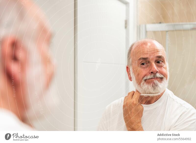 Älterer Mann rasiert Bart mit Klinge Rasieren Vollbart Spiegel zu Hause Morgen Routine Bad Reflexion & Spiegelung positiv Lächeln männlich Senior gealtert älter