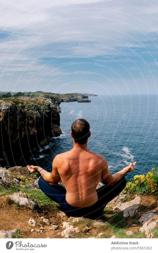 Ein Mann meditiert an einer zerklüfteten Küste mit weitem Meerblick. Meditation Küstenlinie MEER Ansicht felsig Klippe Gelassenheit Himmel Horizont Yoga