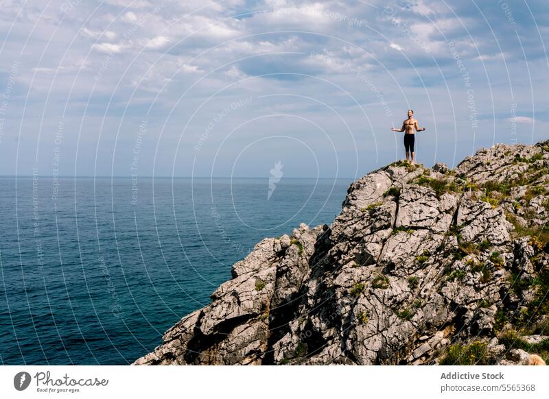 Mann beim Yoga auf einer Klippe am Meer Pose MEER Gleichgewicht Fitness Gesundheit Meditation Ruhe Steine Küste Konzentration Flexibilität Natur im Freien