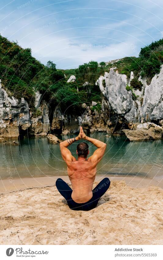 Mann bei der Meditation in einer ruhigen Lagune Lotussitz Strand Klippen Grün Himmel Wolken Wasser Natur Gelassenheit Frieden Erholung Fokus Windstille Sand