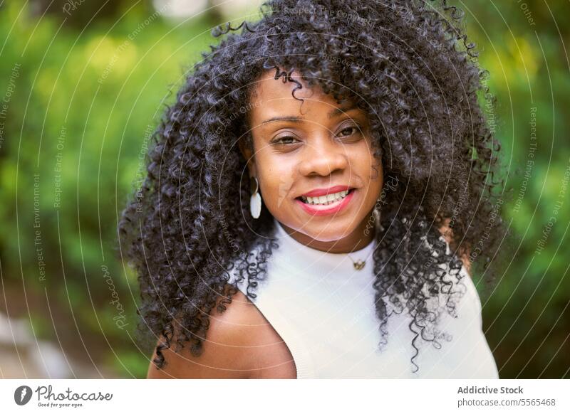 Strahlende Frau genießt die Schönheit der Natur Garten Lächeln krause Haare Porträt Afroamerikaner im Freien Sommer Tag Freude Mode Baum heiter Emotion grün