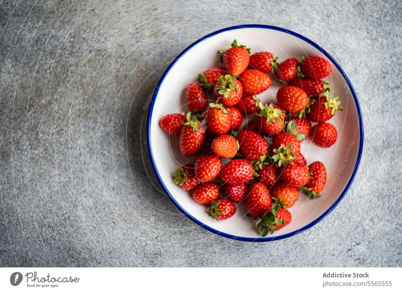 Bio-Erdbeeren auf einem Teller vor einem grauen Hintergrund. organisch rot Frucht frisch reif natürlich Beeren Lebensmittel Gesundheit süß saftig roh Vegetarier