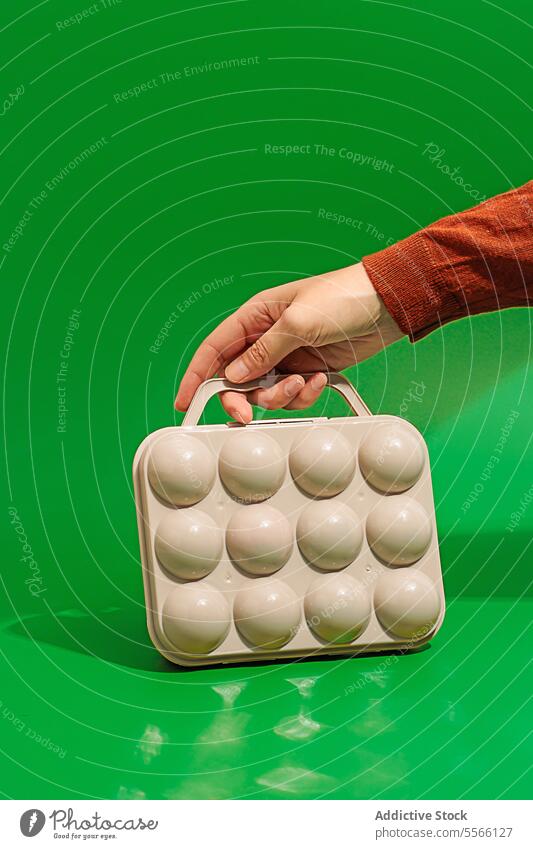 Crop Person Hand mit Golfbällen Box auf grüner Oberfläche Kasten Spiel Sport Kunststoff Ball Körperteil Form Halt spielen zeigen Gerät Kugel Design Farbe Club