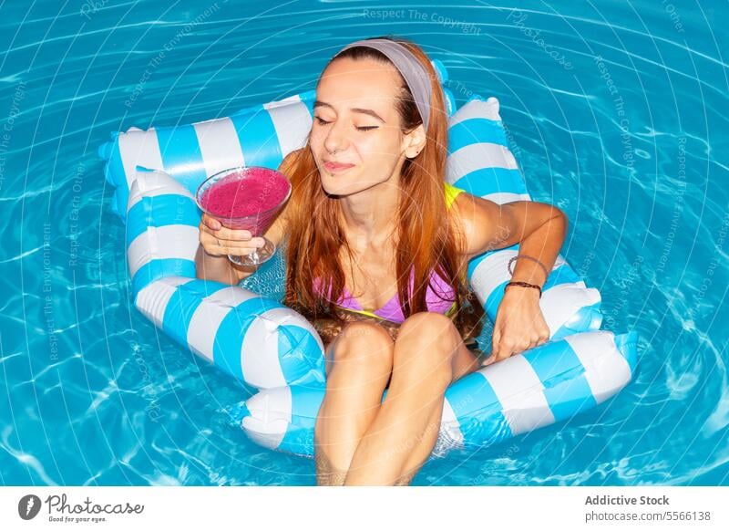 Frau in einem sonnigen Tag Entspannung im Pool mit Cocktail. Sommer trinken aufblasbar Floß blau Wasser Erholung genießend Feiertag Urlaub schwimmen Bräune