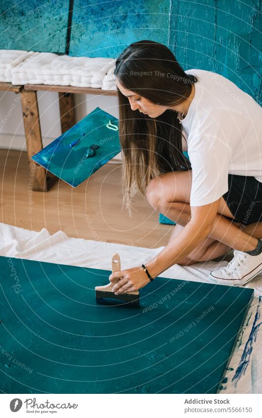 Konzentrierte Künstlerin malt mit Ölfarbe und Pinsel im Atelier auf dem Boden Frau Farbe Pinselblume zeichnen Talent Konzentration kreativ Kunst Anstreicher