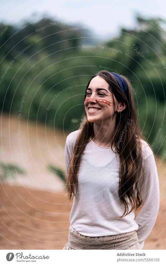 Lächelnde junge Frau, die lachend vor einem unscharfen Hintergrund steht Farbe Natur Wald Glück heiter grün traditionell lässig froh positiv Spaß Optimist