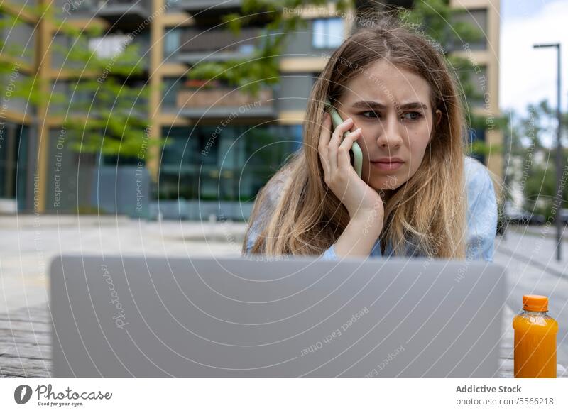 Blondhaarige Frau im Gespräch mit Mobiltelefon im Freien. jung Schüler Kaukasier Gen-Z Mitteilung blond Lügen sprechend Smartphone Vorderansicht Textfreiraum