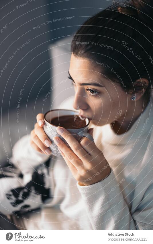 Crop junge Frau sitzt und trinkt Kaffee Tasse Laptop benutzend Internet Anschluss online Wohnzimmer zu Hause dunkles Haar Sofa Apparatur Gerät Getränk Netbook