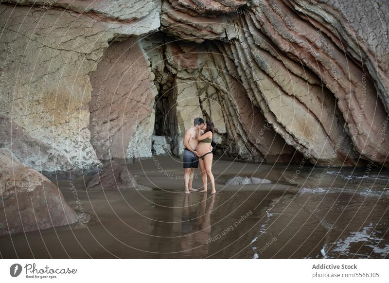 Ein schwangeres Paar küsst sich am Meeresufer Kuss MEER Küste Umarmung Liebe Partnerschaft Mann Frau Umarmen erwarten vorwegnehmen Ufer Zusammensein Urlaub