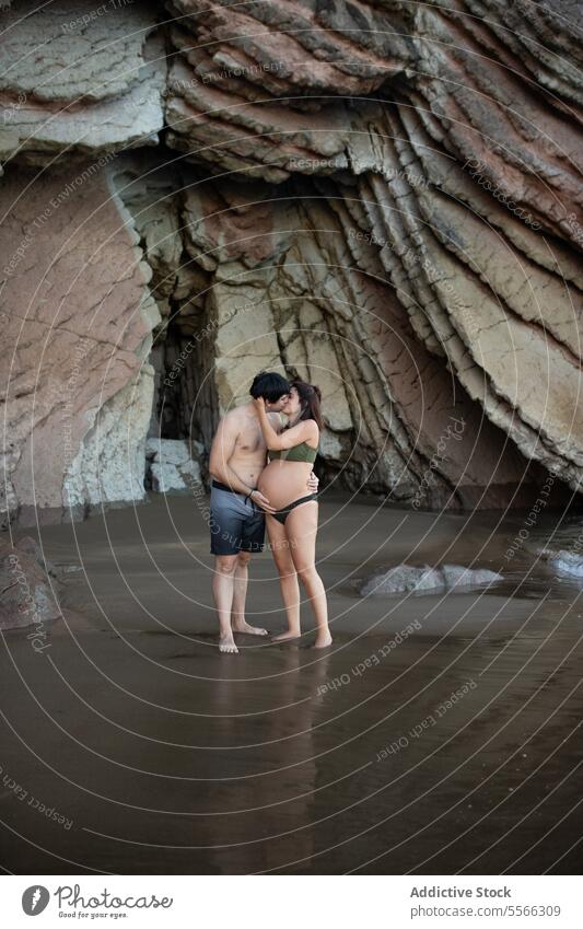 Ein schwangeres Paar küsst sich am Meeresufer Kuss MEER Küste Umarmung Liebe Partnerschaft Mann Frau Umarmen erwarten vorwegnehmen Ufer Zusammensein Urlaub