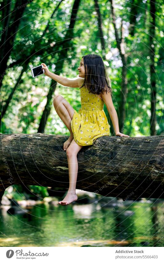 Preteen Mädchen sitzen auf Baumstamm während der Aufnahme selfie Wald Kofferraum Pause Erholung Natur Abenteuer ruhig genießen Sommer Harmonie Feiertag Ausflug