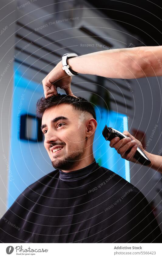 Lächelnde Kundin beim Trimmen des Nackens in einem modernen Friseursalon Klient männlich entgittern Tempel Salon zuschauen Handgelenk Mann Kaukasier Trimmer