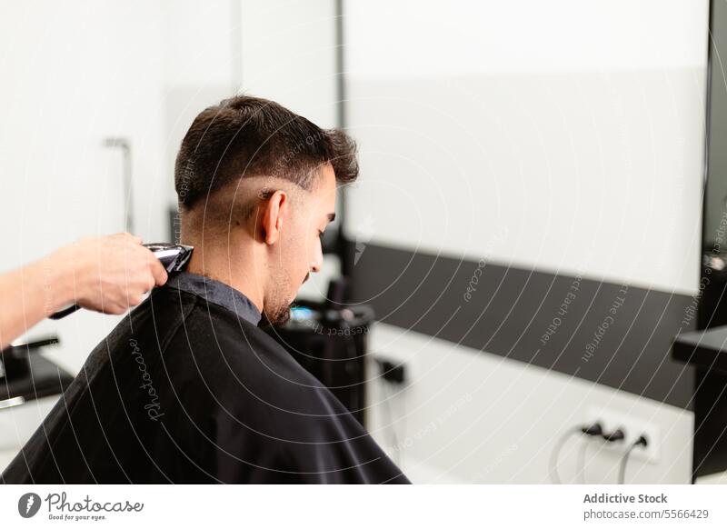 Junger Mann erhält einen sorgfältigen Haarschnitt in einem Friseursalon. Barbershop entgittern Pflege Salon modern präzise Behaarung Stil verblassen Maschine
