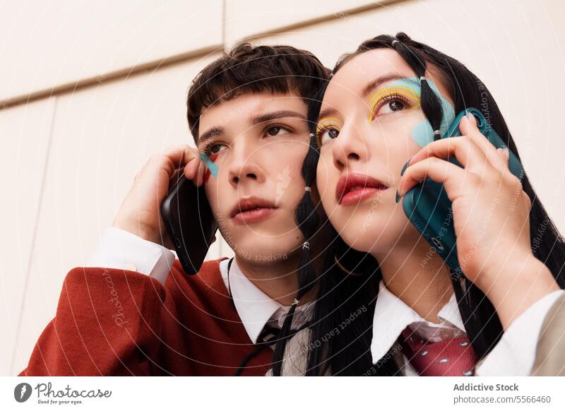 Junges Paar mit lebhaftem Make-up auf Abruf. Jugend Gen-Z Smartphone pulsierend Anschluss Telefon Anruf duo Mode im Freien Gespräch Mobile Zeitgenosse Stil