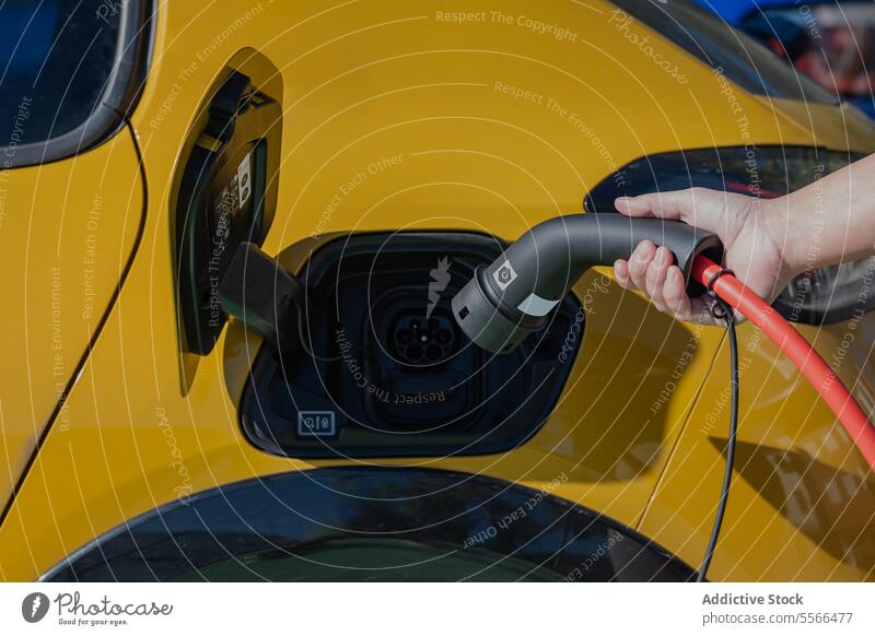Anonyme Person, die an einer Tankstelle ein Ladekabel in ein Elektrofahrzeug steckt Station elektrisch Ladegerät Kraft Fahrzeug PKW Ökologie Verkehr Energie