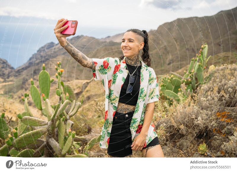 Tätowierte Frau nimmt Selfie gegen Berge stylisch Natur Tattoo Stehen attraktiv jung Mode hübsch Stil cool Schönheit trendy lässig modern niedlich modisch