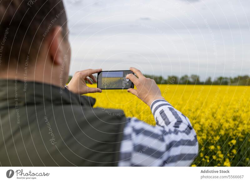 Ein erwachsener Mann, der die Blüte der Natur mit dem Smartphone-Objektiv einfängt. einfangen Blume Feld gelb Fotografie Telefon Blütezeit im Freien Frühling