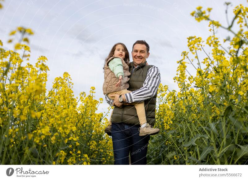 Vater und Tochter genießen die Zeit in einem gelben Blumenfeld. Feld binden Familie Fröhlichkeit Rap Natur Eltern Kind Porträt Liebe im Freien