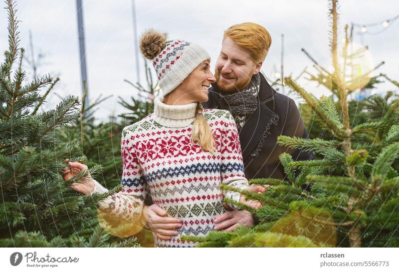 glückliches Paar in der Liebe Kauf Weihnachtsbaum auf der Straße Markt in Abend. Winterurlaub und Menschen Konzept Bild betrachten Kuss Familie Glück Rotschopf