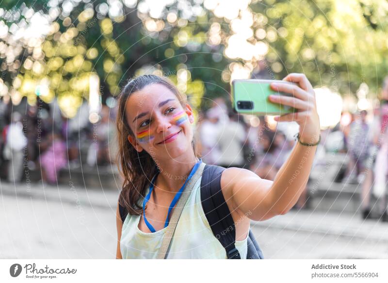 Frau macht Selfie bei Pride-Veranstaltung Stolz im Freien Gesicht Farbe Streifen Freude Telefon Lächeln Feier Tag verschwommen Hintergrund Teilnehmer Stadtfest