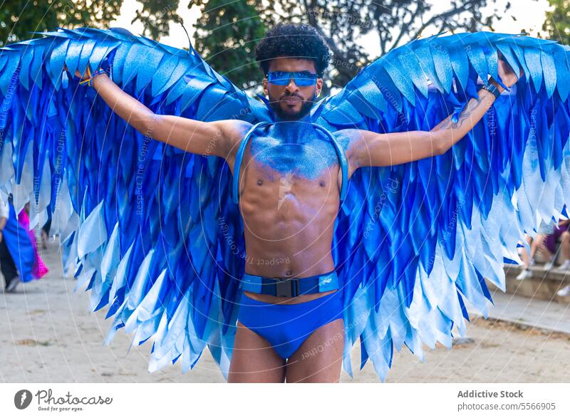 Schwarzer blauer Flügel, der während einer LGBT-Pride-Veranstaltung im Freien steht Mann Baum selbstbewusst Sonnenbrille mystisch Farbe pulsierend schmücken