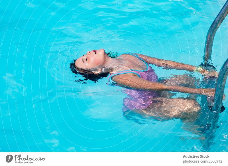 Ein Kind schwimmt im Pool und hält sich an einer Leiter fest. Schwimmer Laufmasche blau Badeanzug purpur Anmut Frieden Sommer Wasser schwimmen Halt Metall