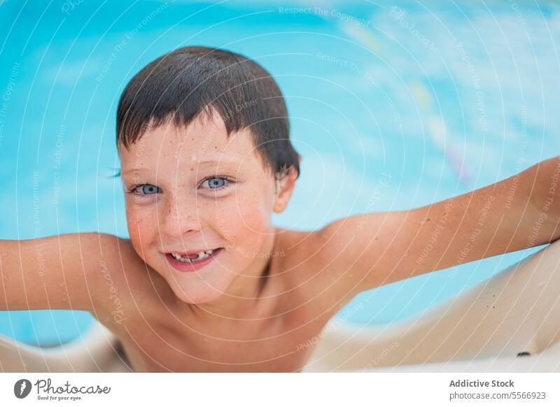 Lächelnder Junge, der auf der Schwimmbadrutsche in die Kamera schaut. Pool blau Auge Saum Wasser fettarm schwimmen Kind Freude Sommer nass Haut Badebekleidung