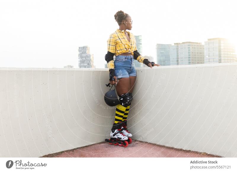 Nachdenkliche Frau in Rollschuhen mit Helm im Skatepark nachdenklich Schutzhelm Wegsehen Rolle Schlittschuh Wand Sonnenlicht Ausrüstung Stehen lässig Hemd
