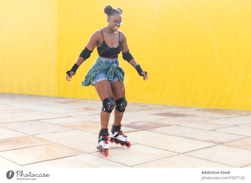 Glückliche junge Frau auf Rollschuhen im Skatepark Rolle Schlittschuhlaufen Lächeln lässig Wand gelb Skateplatz Sport üben Freizeit Wochenende Aktivität Sommer