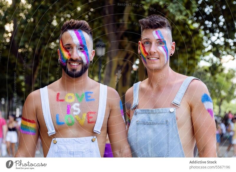 Zwei Männer im Regenbogenstolz Mann duo Gesicht Farbe Stolz lgbtq Feier Straße Porträt Baum Nachricht Liebe Truhe freudig pulsierend Glück Ausdruck abstützen
