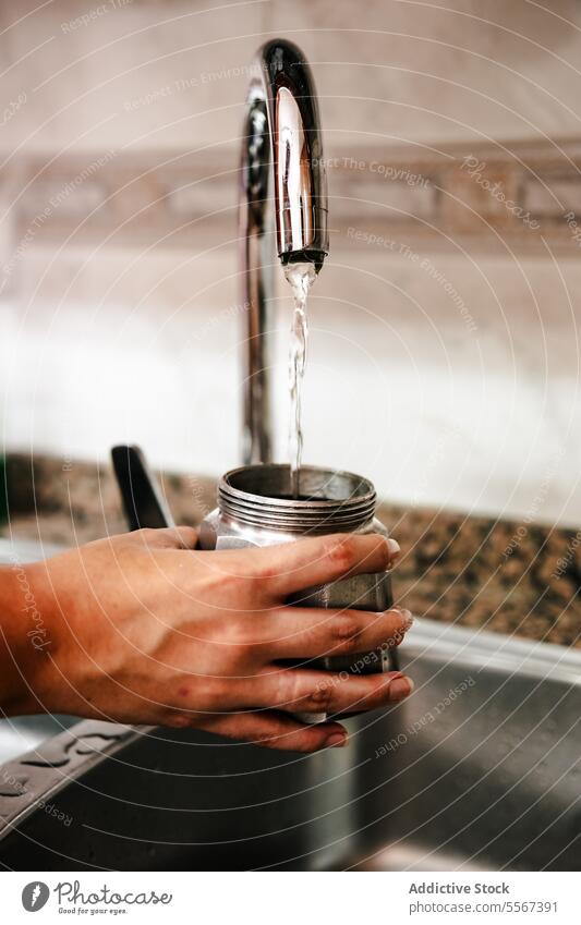 Füllen der Mokakanne mit Wasser Hand Mokka Topf Italienisch Kaffee Brotbelag Wasserhahn Küche Waschbecken Vorbereitung heimwärts traditionell Nahaufnahme