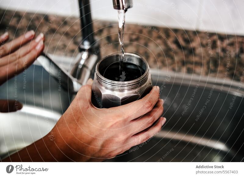 Füllen der Mokakanne mit Wasser Hand Mokka Topf Italienisch Kaffee Brotbelag Wasserhahn Küche Waschbecken Vorbereitung heimwärts traditionell Nahaufnahme