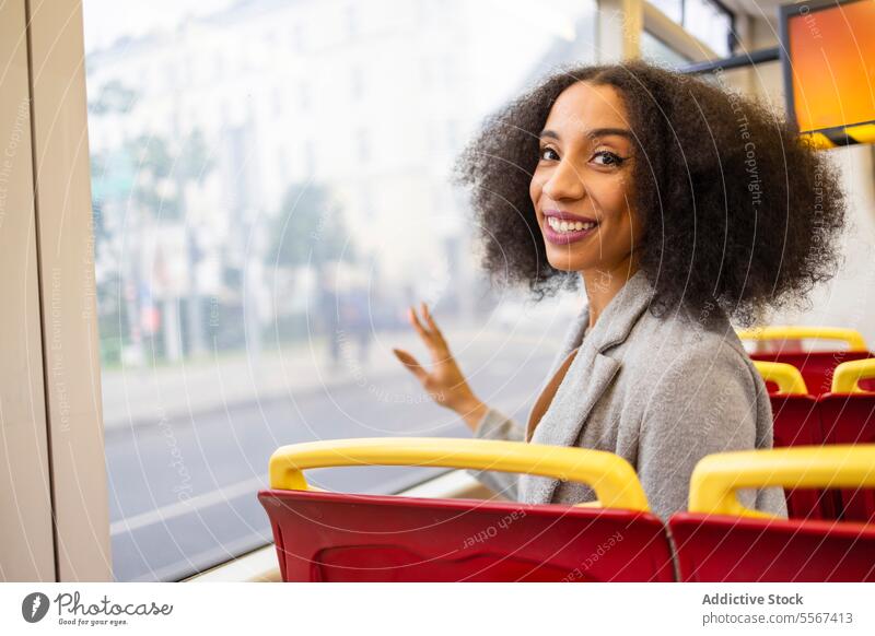 Glückliche Afro-Frau beim Sitzen auf einem Bussitz lockig Behaarung Fenster Reflexion & Spiegelung Großstadt Transport Freude Wachtraum rot Arbeitsweg