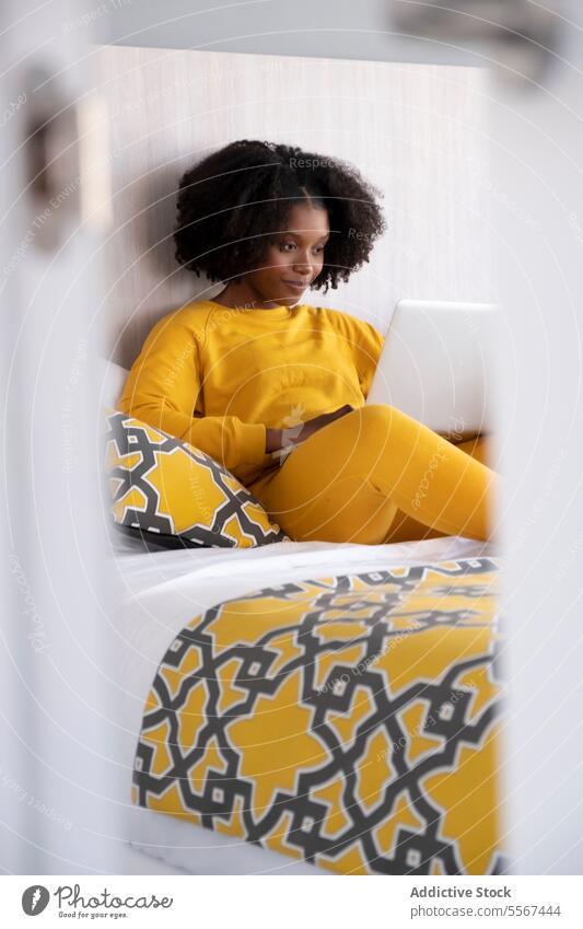 Schwarze Frau im digitalen Moment zu Hause gelb Laptop Bett Kissen Raum Licht Innenbereich Kleidung Technik & Technologie heimwärts sich[Akk] entspannen lernen