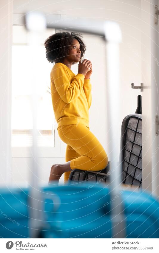 Schwarze Frau, die über eine Reise nachdenkt gelb Koffer Fenster nachdenken reisen jung Denken fettarm krause Haare im Innenbereich Raum Reflexion & Spiegelung