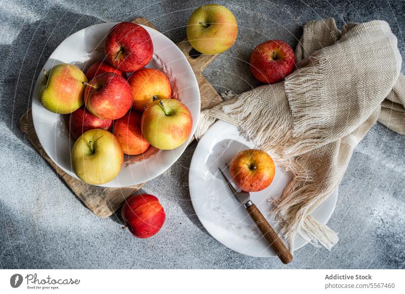 Äpfel in rustikalem Ambiente Apfel reif farbenfroh Holz Holzplatte Teller weiß Gabel Gewebe Küche Einstellung Frucht rot gelb saisonbedingt frisch Natur