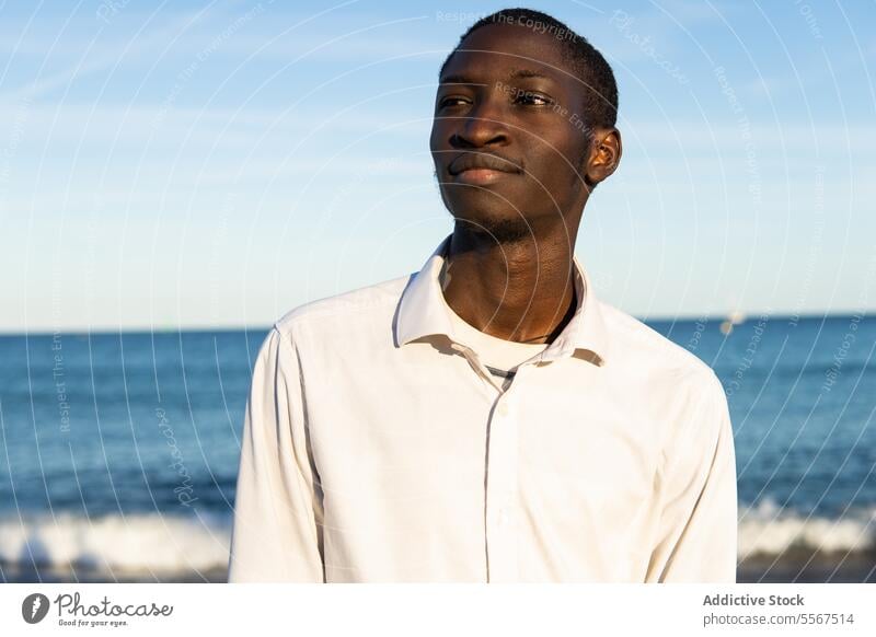 Junger Mann, der den Strand betrachtet Meer Horizont Hemd weiß jung Windstille Gelassenheit Porträt Starrer Blick beschaulich Himmel blau Wasser Ufer