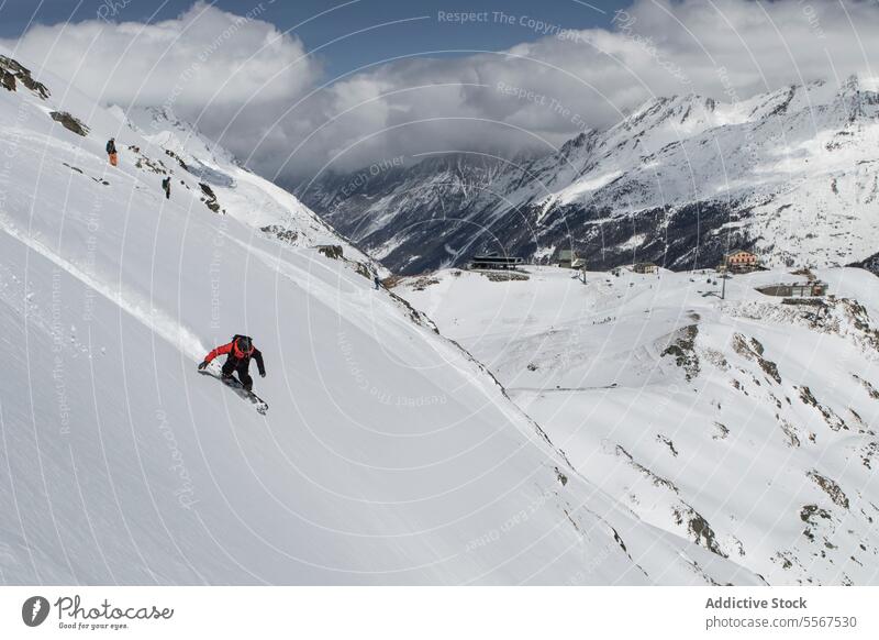 Snowboarder beim Fahren am Berghang im Urlaub unkenntlich Berge u. Gebirge Person Schnee Reiten deckend Snowboarding warm Anzug wolkig Himmel Schweizer Alpen