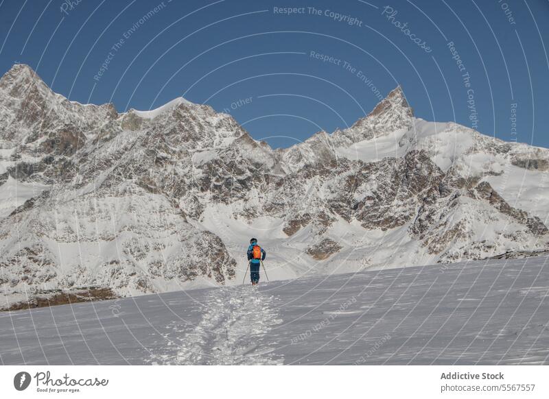 Person mit Skistöcken auf einem schneebedeckten Berg im Urlaub Ganzkörper Rückansicht unkenntlich Mast laufen Schnee deckend Berge u. Gebirge sonnig Abenteuer