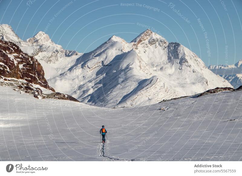 Person mit Skistöcken auf einem schneebedeckten Berg im Urlaub Ganzkörper Rückansicht unkenntlich Mast laufen Schnee deckend Berge u. Gebirge sonnig Abenteuer