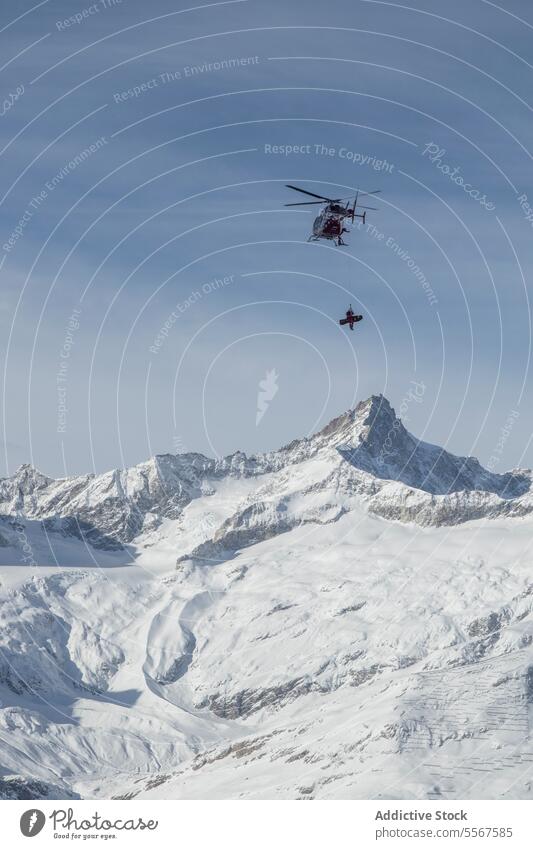 Snowboarder hängt aus Hubschrauber über Schneeberg erhängen fliegen reisen deckend Transport Berge u. Gebirge Landschaft Himmel Schweizer Alpen Bewegung