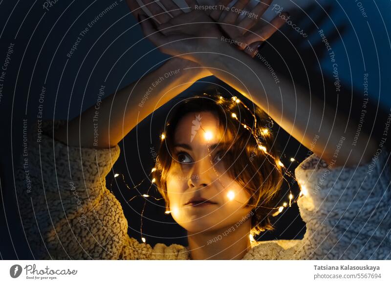 Porträt einer Frau im Dunkeln mit Lichterkette dunkel Lichterketten Schnur beleuchtet verwickelt Nacht Kopf Abend elektrisch Kurze Haare Weihnachtsbeleuchtung
