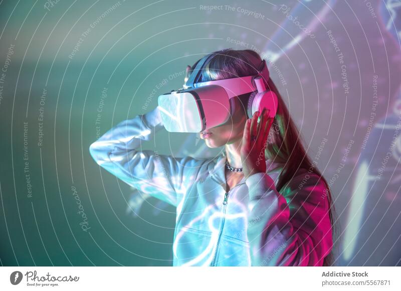 Anonyme Frau mit VR-Brille erkundet den Cyberspace auf glühenden Lichtern Schutzbrille erkunden Virtuelle Realität jung Headset Simulator erweitert Innovation