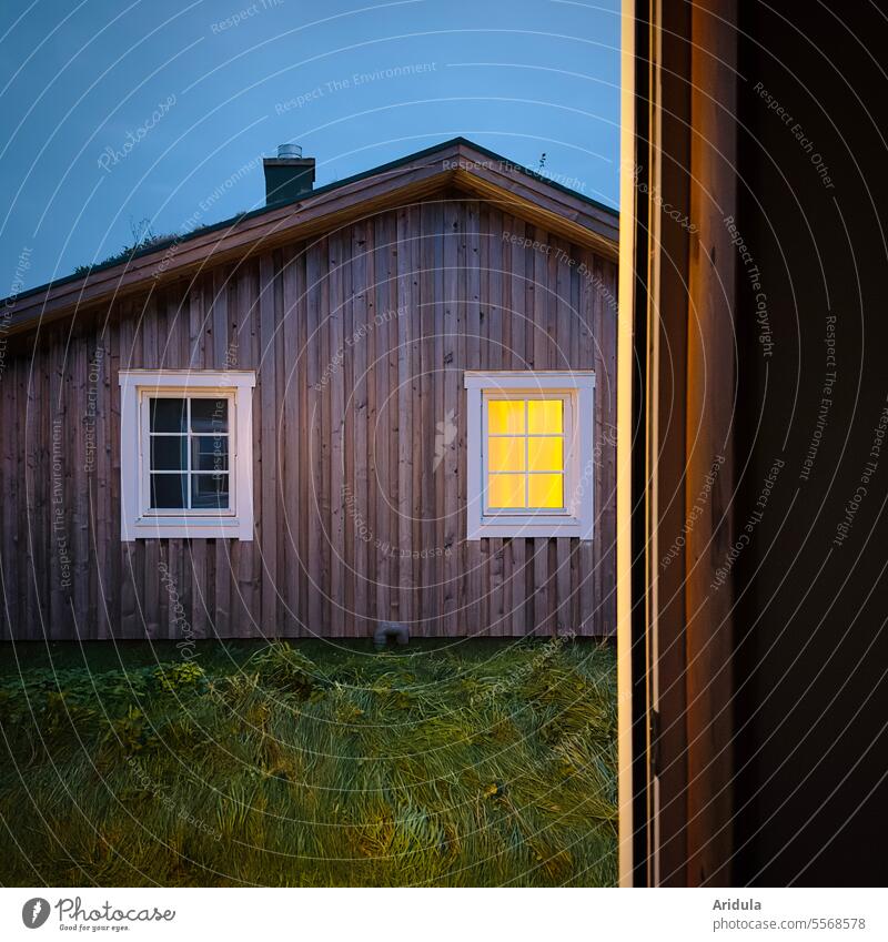 Haus mit erleuchtetem Fenster am Abend Licht Dämmerung Holzhaus gemütlich Holzhütte Hütte Sprossenfenster Gebäude Abenddämmerung Abendstimmung