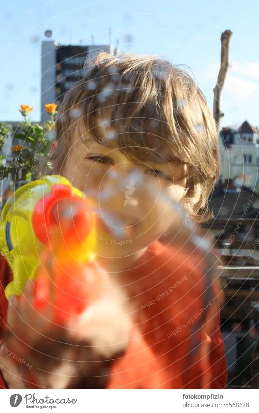 Kind schießt mit Wasserpistole schießen frech Spiel Spass Fröhlichkeit Kindheit Spielen Junge Spaß spielen Gesicht direkt Sommer zielen spritzen Spritzpistole