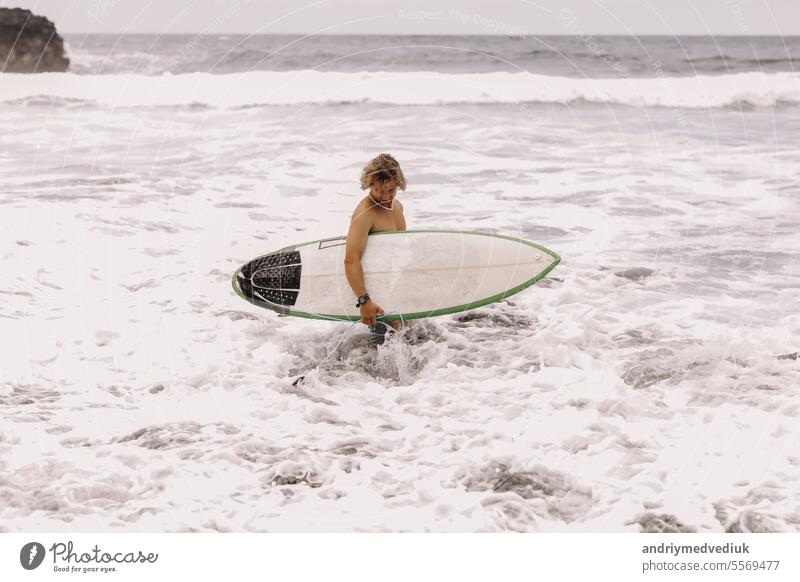 junge fit Surfer Mann mit Surfbrett läuft in Ozean oder Meer mit großen Wellen zum Surfen. Konzept der extremen Sport, Fitness, Freiheit, Glück, neue moderne Leben. Sport Reiseziel.