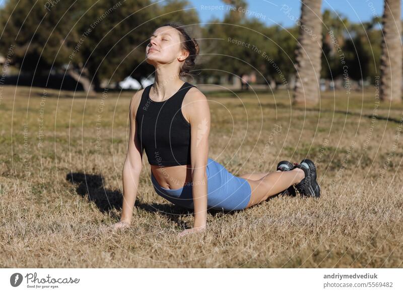 Weltgesundheitstag. Schöne fit junge Frau in sporswear arbeiten im Freien im Park, tun Stretching-Übungen stehen in Pose Hund Schnauze nach oben, Sonnengruß komplex. Aufwärtsgerichteter Hund Zusammenbruch