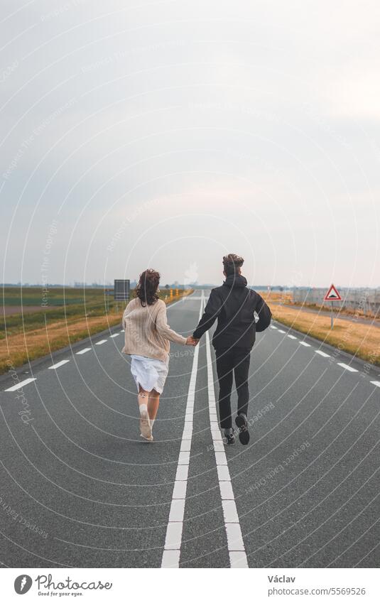 Junges liebendes Paar läuft zusammen, um neue Abenteuer in Almere, Niederlande, während des Sonnenuntergangs zu erleben Zusammensein Freund Freundin rennen